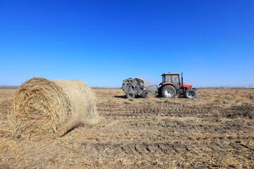Obraz premium Farmers use agricultural machinery to bind straw in the field, North China