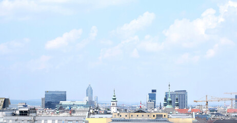Fototapeta premium View of Vienna city center. Buildings, roof tops, cranes and blue sky with clouds. Vienna, Austria