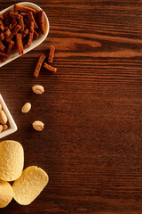 Overhead view of wooden table framed with snacks, nuts and chips. Copy space