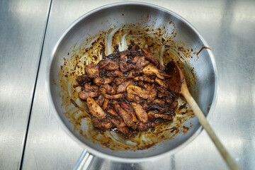 the process of cooking chicken in teriyaki sauce. cooking chicken in sweet and sour sauce. chicken pieces with teriyaki sauce in a metal bowl