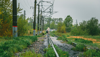 The girl crosses the railway tracks in the wrong, dangerous place. A girl walks next to a railway...