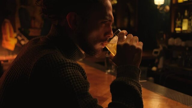 Portrait of a young guy in a night bar. A man drinks a cocktail and rests.