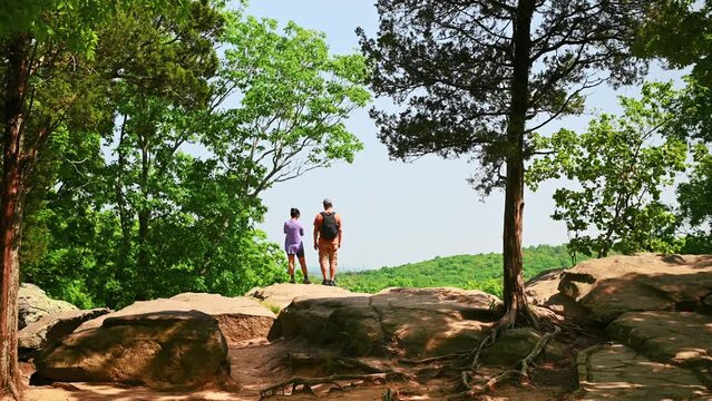 A couple is standing on a hill and the girl is taking pictures of the mountain with her mobile in the Garden of the Gods