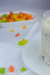 Colored candied fruits of mango, passion fruit and other fruits in a white spoon lie on the table.