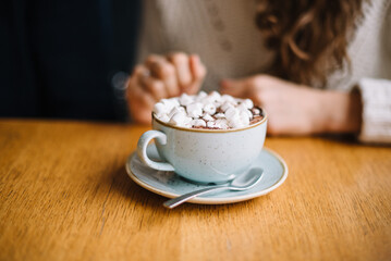 Hot chocolate cacao with marshmallows on a wooden table in cafe 