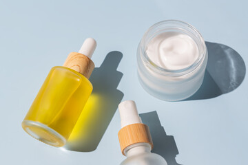 natural luxury cosmetics - face cream and beauty serum or essence with vitamin C or collagen for skin care. Unbranded mockup cosmetics on blue background with copy space