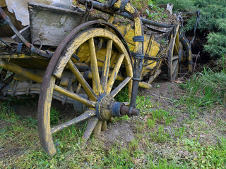 Rusty wreck of a vintage old cart  stuck in the ground overgrown with grass