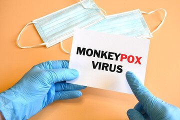 Doctor hand in blue glove indicate Monkeypox Virus words on white paper. Monkeypox on white paper....