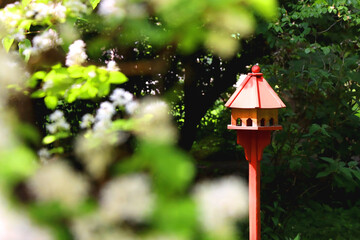 Cute red birdhouse in the beautiful park. Beautiful spring or summer day. Selective focus.