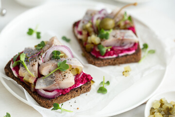 Smorrebrod with dark rye bread, herring, pickled cucumber and beet mousse. Smorrebrod. selective...