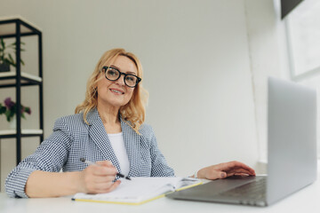 portrait an attractive mature businesswoman working on laptop in her workstation