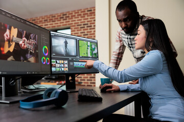 Professional digital movie editor sitting at desk while improving film frames and improving footage quality. Post production house team leader talking with coworker about quality of frames. - obrazy, fototapety, plakaty