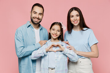 Young parents mom dad with child kid daughter teen girl in blue clothes show shape heart with hands heart-shape sign hug isolated on plain pastel light pink background Family day parenthood concept.