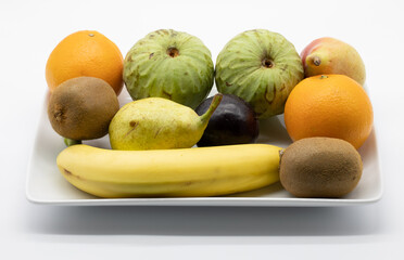 Variety of fresh fruit in a ceramic tray isolated on a white background