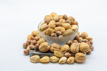 Glass bowl full of walnuts with a nutcracker isolated on a white background