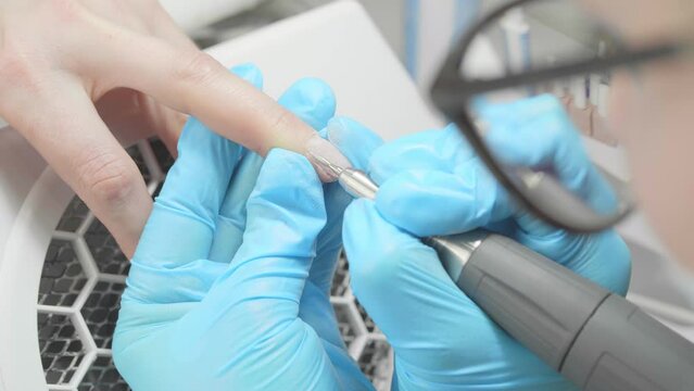 Manicurist professionally makes a manicure with a device