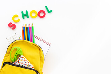 Yellow school backpack with colorful school stationery