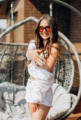 Bachelorette party. Happy future bride in a white shirt and shorts poses on the roof of the house overlooking the city.