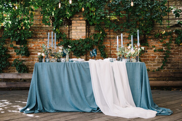 Stylish wedding table decoration and table setting. Blue tablecloth. Outdoor wedding party. Vintage...