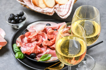 Food aperitif  prosciutto ham, parma ham, salami, olives and  bread. Charcuterie plate. Two glasses of white wine or prosecco