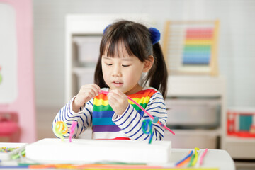 young girl threading beads making craft for home schooling