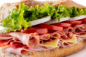 Submarine sandwich with ham, cheese, lettuce, tomatoes,onion, mortadella and sausage. Close up