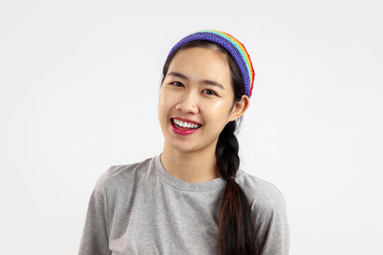 Photo of happy asian woman with rainbow headband isolated white background. LGBT pride month concept
