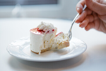 Red and white cake being cut with fork in female hand.