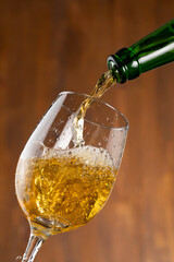 Pouring beer into a stemmed glass. Jet of luxury beer out of the bottle is poured into a beer glass, causing a lot of bubbles, foam and bubbling liquid. Studio photo shot.