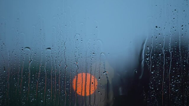 Moody rain on window during storm with bokeh traffic lights