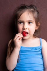 Young girl eats fresh red strawberry