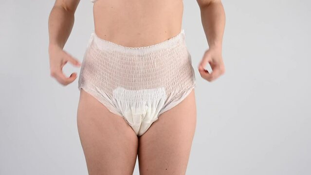 A faceless woman adjusts the elastic of adult diapers. Incontinence problem.