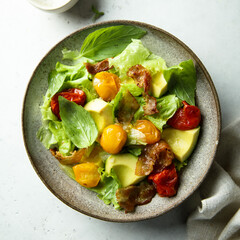 Homemade salad with toasted tomatoes, avocado and bacon