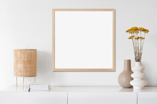 Blank picture frame mockup on white wall. Artwork in minimal interior design. View of modern boho style interior with canvas for painting or poster on wall. Minimalism concept
