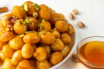 luqaimat fried dough in deep-fried balls sprinkled with sweet honey syrup, close-up, light background.