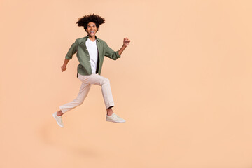 Fototapeta na wymiar Full length body size view of attractive cheerful guy jumping running great success isolated on beige pastel color background