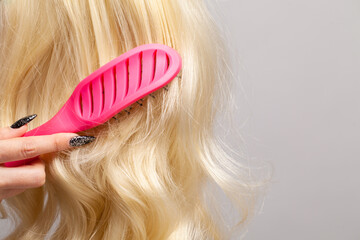 Pink plastic comb and blonde hair closeup