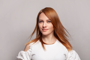 Cheerful woman with red ginger hairstyle posing on grey studio background