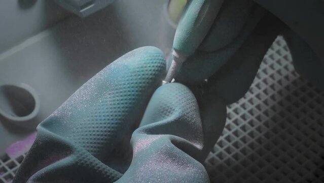 Operating a sandblaster device to polish the metal tooth. Professional cleaning device is used on the metal tooth. Stomatology device is finishing surface of metal tooth crown. Dentistry equipment