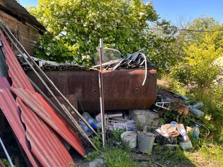 Abandoned rusty and plastic waste in the forest. Metal debris left in the garden impact on our...