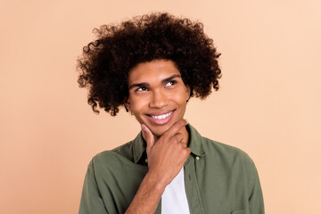 Fototapeta na wymiar Portrait of attractive bewildered cheerful wavy-haired guy touching chin brainstorming isolated over beige pastel color background
