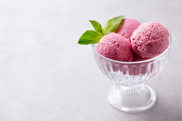 Strawberry ice cream in a glass bowl on grey background. Close up. Copy space.