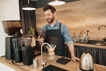 Positive Barista holding a container with coffee beans before installing in the coffee machine