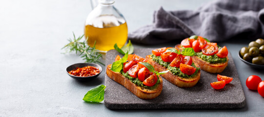 Bruschetta with pesto and tomatoes. Gray stone serving board. Copy space. - 507269563