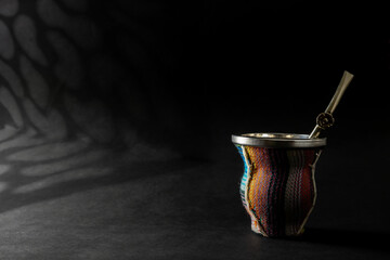 Beautiful colorful mate cup with bombilla on black background. Copy space for your design. Web...