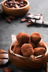 Chocolate truffles with cocoa powder in wooden dish on old dark concrete table background. Tasty sweet chocolate truffles candies. Valentines Day and Mothers Day concept with copy space. Top view.