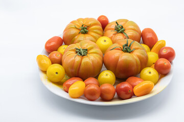 Different types of tomatoes, for salad, pear, colorful cherry in a bowl on a white background