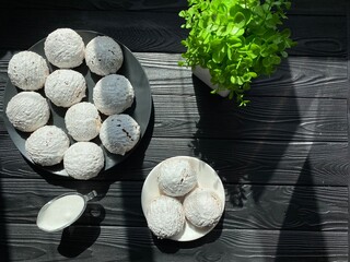 Buns on black and white plates. Utensils in white and black color on a dark wooden table. Decorative flower on the kitchen table.