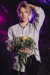 Dziewczyna w koszuli z bukietem kwiatów w opuszczonej szklarni - obrazy, fototapety, plakaty