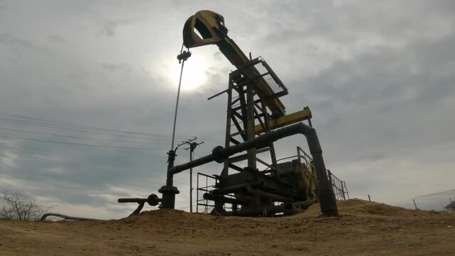 Pump jack for crude oil. Oil rocking chair. Oilfield. Oil well. Silhouette Oil Extraction Plant